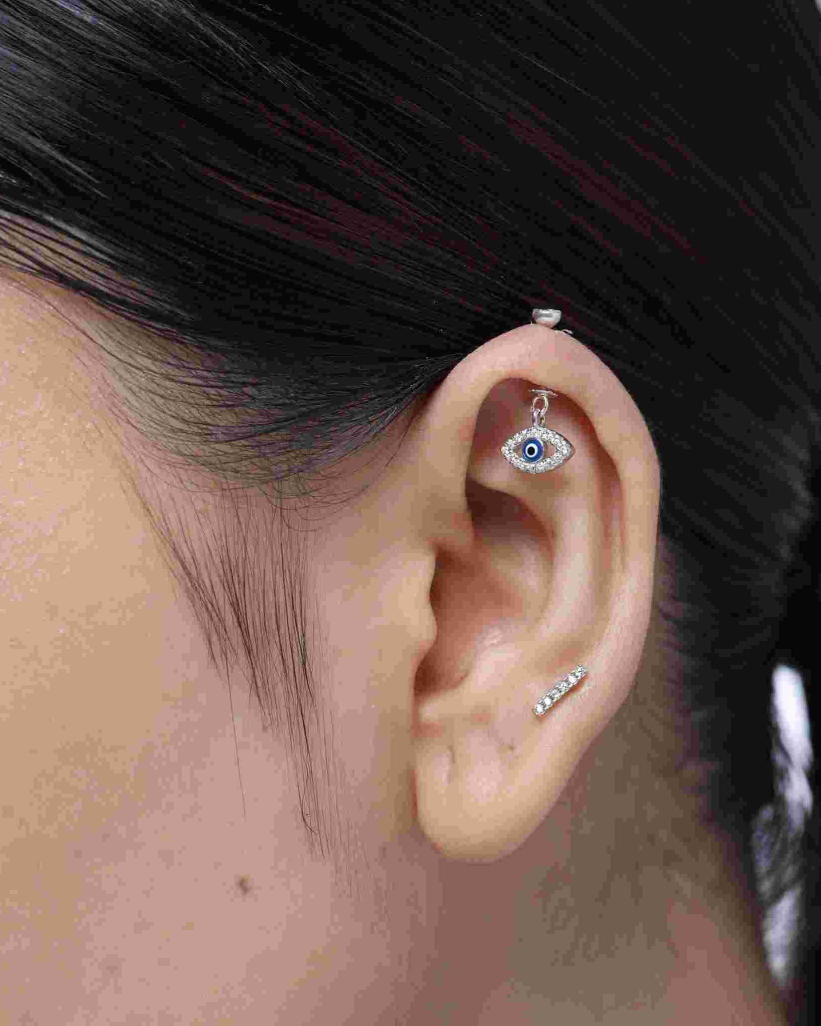 Close-up of Enamel Blue Evil Eye Helix Piercing with Pavé Zircon Stones on ear, highlighting the detailed design and sparkling cubic zirconia setting.